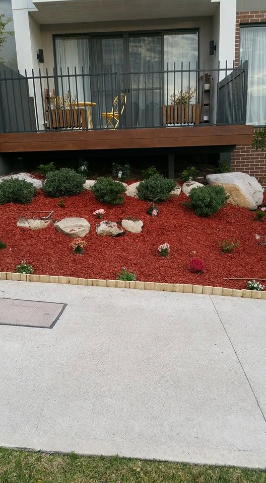 Front garden bed after maintenance with fresh red mulch and rock features