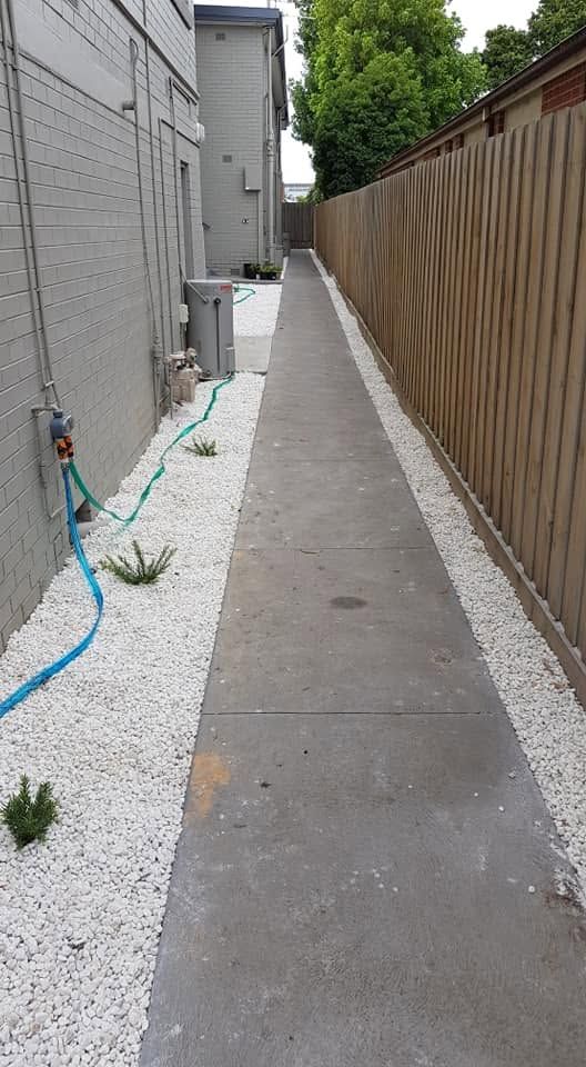 Side path finished with white pebble border along the fence