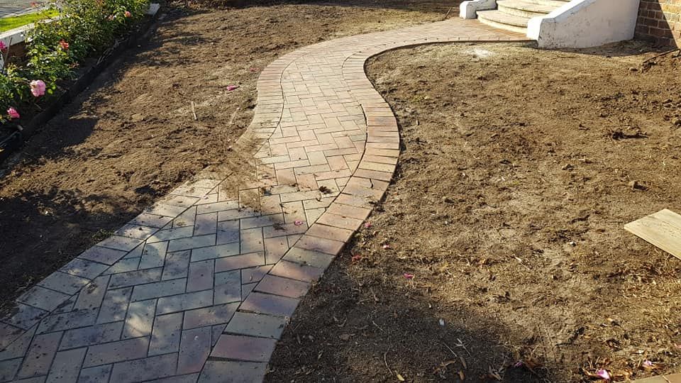 Yard before turf with curved brick path through bare dirt